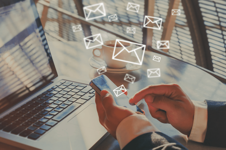 Person sending out emails on phone and computer