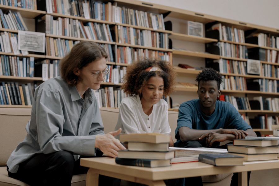 Three teenagers at a library with books