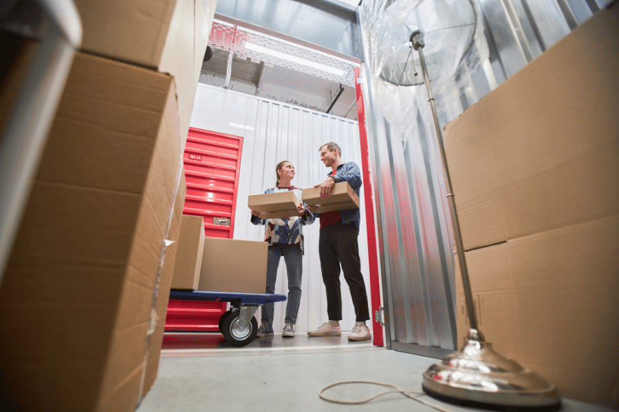 couple loading boxes of items into storage facility with red doors
