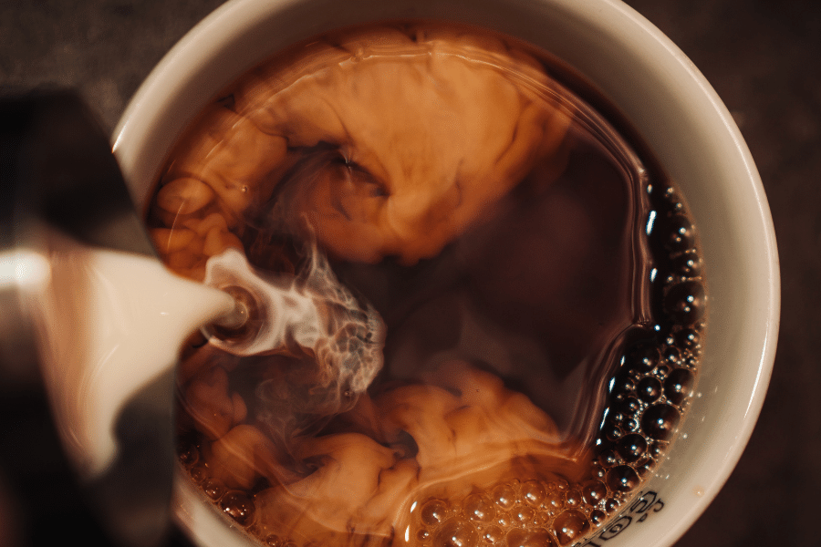 Pouring creamer in coffee