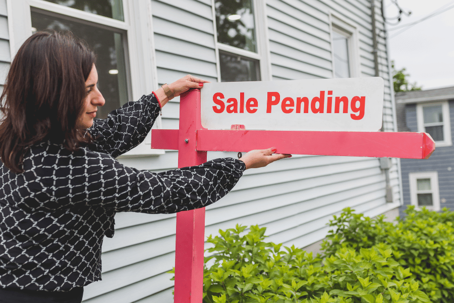 woman putting up a sale pending sign in a yard