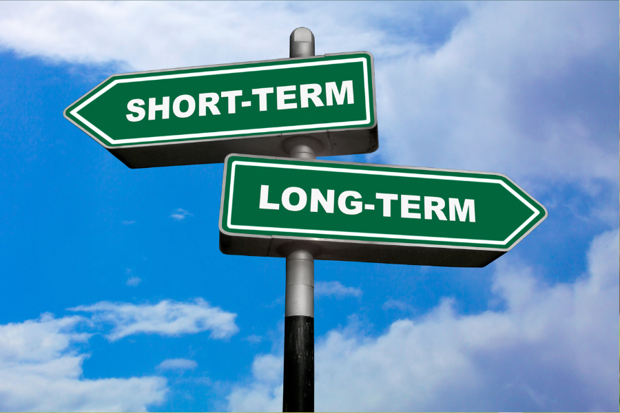 Green arrow with word short term and green arrow with word long term with blue sky and clouds in the background