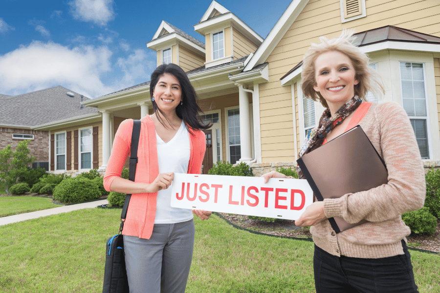 realtors holding a new home listing sign 