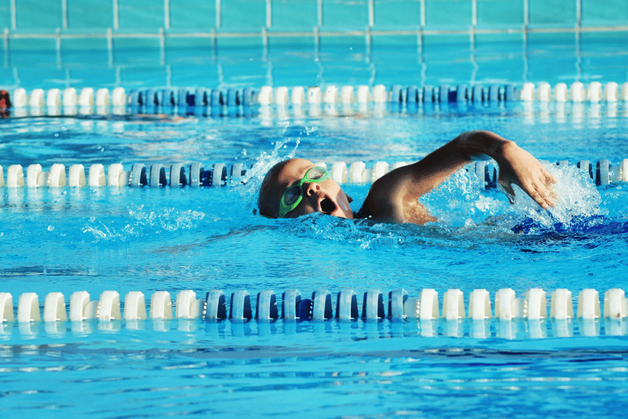 kid swimming laps at an outdoor pool with swim googles 