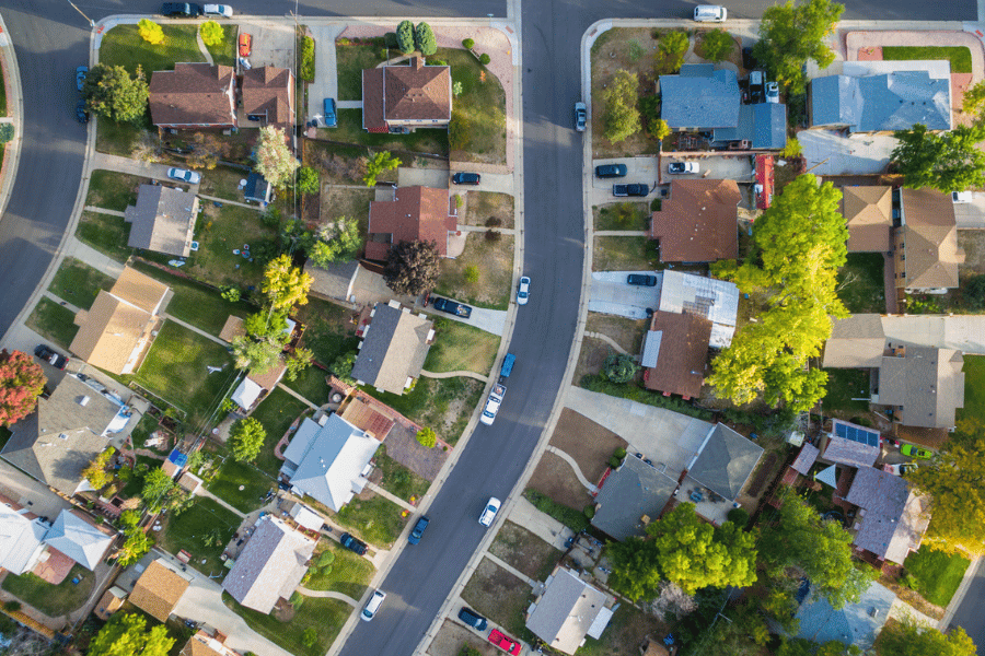 Aerial view of a popular neighborhood with cars parked on the street and green grass