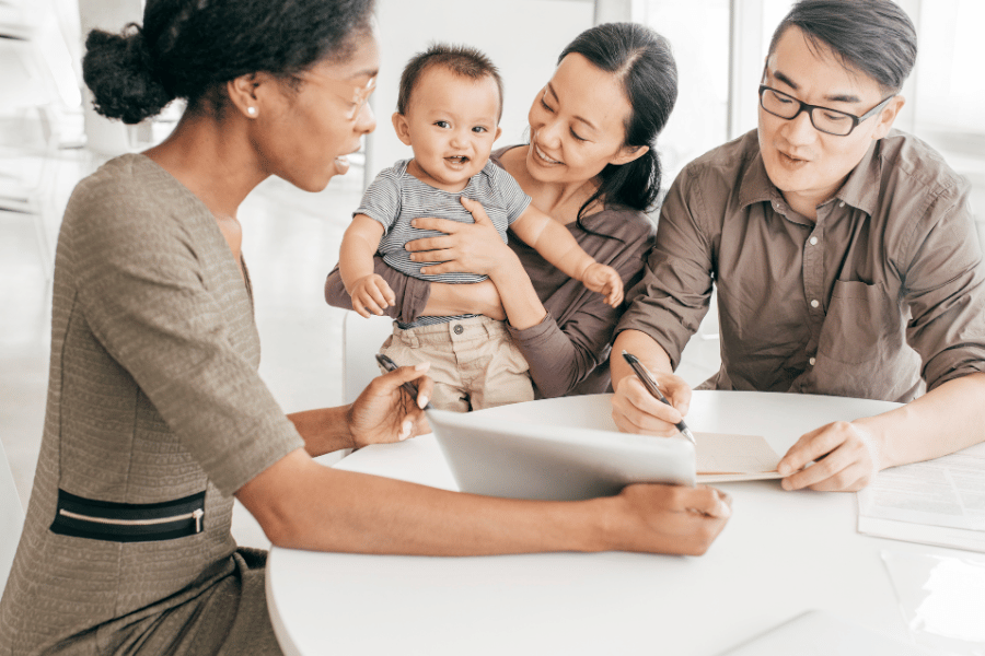 young family with child sitting at a table to sign a document