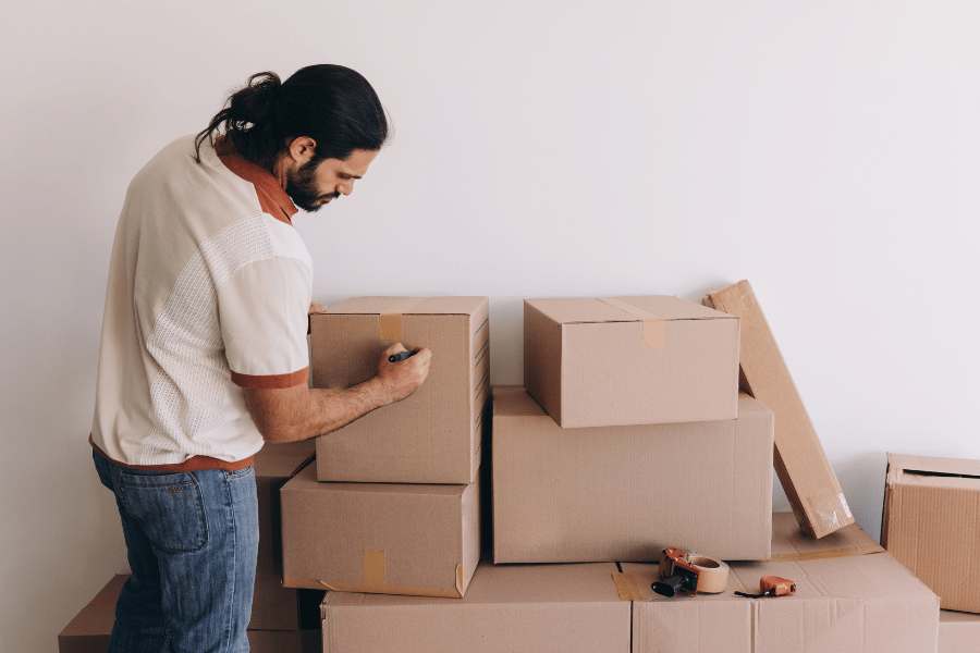 Man labeling packing boxes with a permanent marker